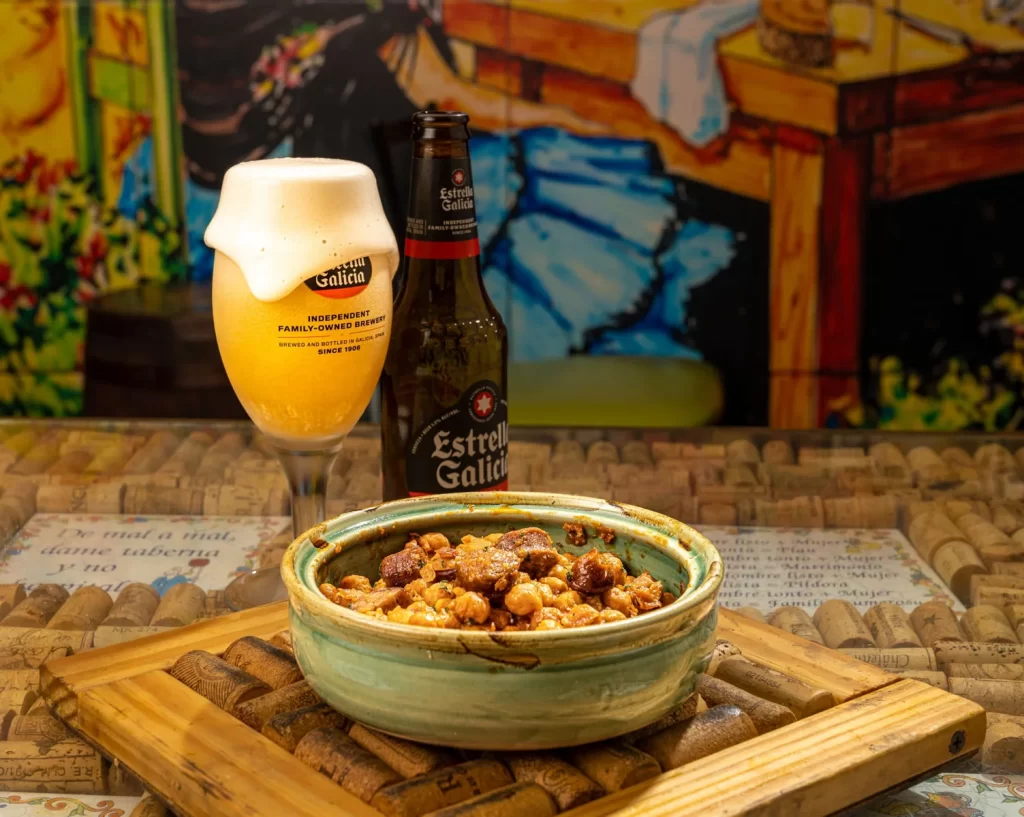 Chorizo and chickpeas tapa served with Estrella Galicia beer at El Pimiento Restaurant, the best Spanish restaurant in Miami Lakes
