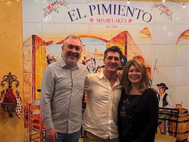 Basque painter Iñigo Manterola with the owners of a Spanish restaurant in Miami Lakes, standing in front of the hand-painted tile mural