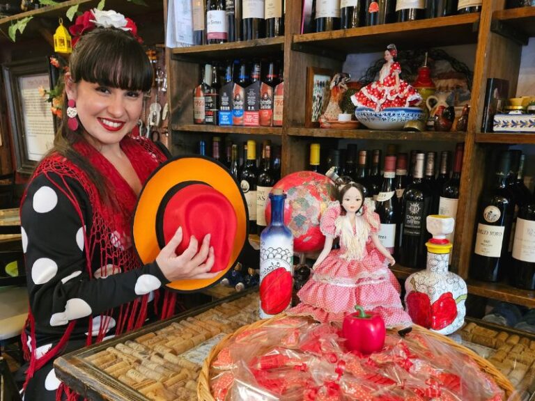 Flamenco dancer in a polka dot dress holding a traditional hat beside a basket of red party favors at El Pimiento Restaurant in Miami Lakes