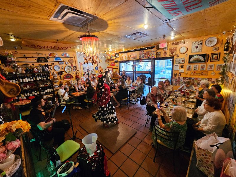 Guests celebrating at long tables while a guitarist and flamenco dancer perform in the dining room of El Pimiento Restaurant in Miami Lakes